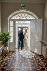 Bride and groom looking at each other, stood under an interior doorway at Marshall Meadows Manor